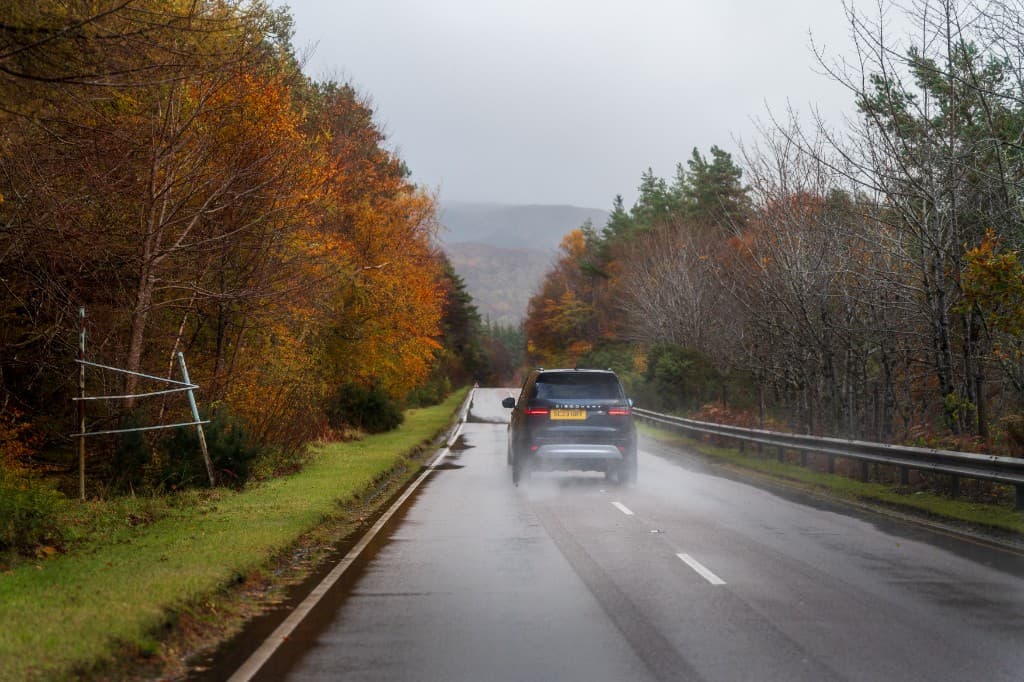 Car driving on a wet forest road near London